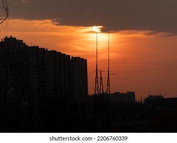 Sunset in the big city between buildings and transmission towers in the shadow with the big sun in the background. - Powered by Shutterstock