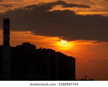 Sunset in the big city between buildings and transmission towers in the shadow with the big sun in the background. - Powered by Shutterstock