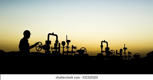 Sunset Blue Hour And Silhouette Of Oilfield Worker At Oil Well Manifold  