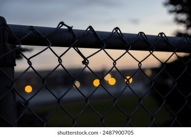 Sunset bokeh lights behind chain-link fence - blurred urban background with warm glowing orbs - dusk sky gradient - Powered by Shutterstock