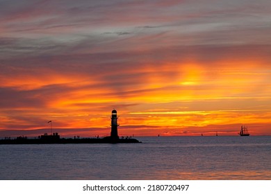 Sunset at bulwark, harbor entrance with lighthouse, Warnemunde, Rostock, Mecklenburg-Western Pomerania, Germany - Shutterstock ID 2180720497