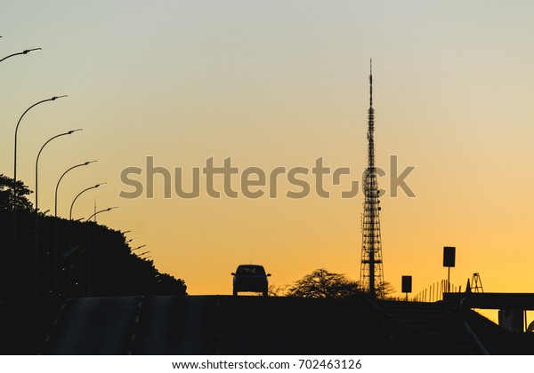 Sunset, a car and tv tower of Brasilia, Federal\
District, Brazil.