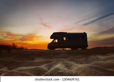 Sunset And Caravan Silhouette. Van Life Concept. Travelling In The Europe. Camper Van On The Beach.