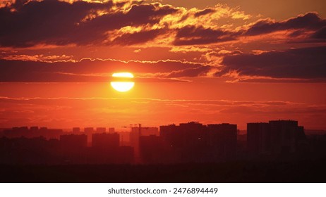 The sunset cast a red glow on the clouds above the evening city skyline with its tall rooftops, time lapse. - Powered by Shutterstock