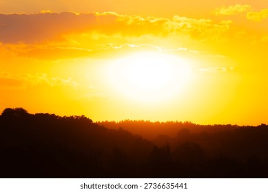 Sunset casting a warm glow over the horizon with silhouettes of trees near a tranquil landscape