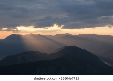 Sunset casts light over mountain ranges creating a dramatic landscape view in the evening sky
