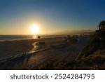 A sunset casts vibrant colors over a beach with palm trees Santa Monica