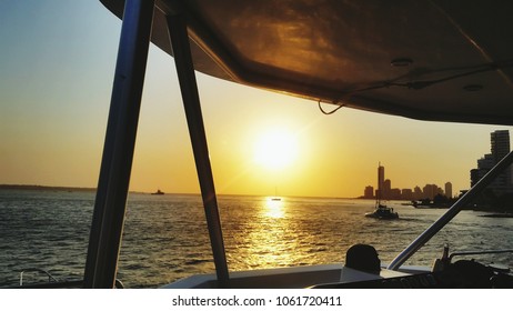 Sunset cityscape modern buildings, seascape with boats view from boat.