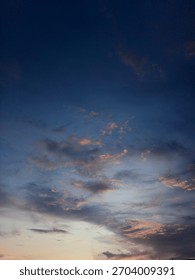 ​Dramatic sunset clouds fill a deep twilight sky, highlighted by streaks of orange and pink light near the horizon.The dark,intense blue dominates the upper frame,creating a striking moody atmosphere.