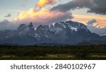 Sunset clouds glow above dramatic snow-covered peaks in Patagonia.