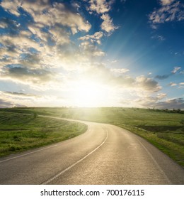 Sunset In Clouds Over Asphalt Road To Horizon