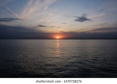 sunset in the clouds with sea view and reflection on the water