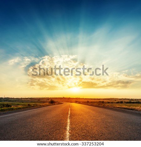sunset in clouds with sunrays over road to horizon