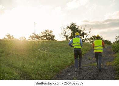 Sunset at construction site with two construction workers walking away at the end of their shift, cinematic shot