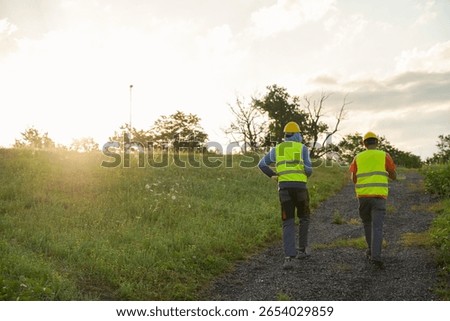 Sunset at construction site with two construction workers walking away at the end of their shift, cinematic shot
