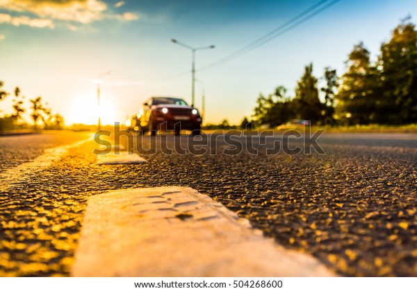 Sunset in the country, the car\
on the highway. Wide angle view of the level of the dividing\
line