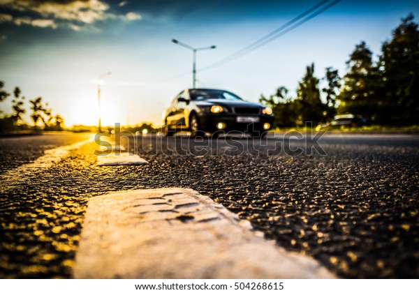 Sunset in the country, the car on the highway. Wide\
angle view of the level of the dividing line, image vignetting and\
the hard tones