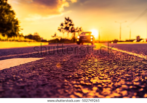 Sunset in the country, the car rides on the\
highway. Wide angle view of the level of the dividing line, image\
in the orange-purple\
toning