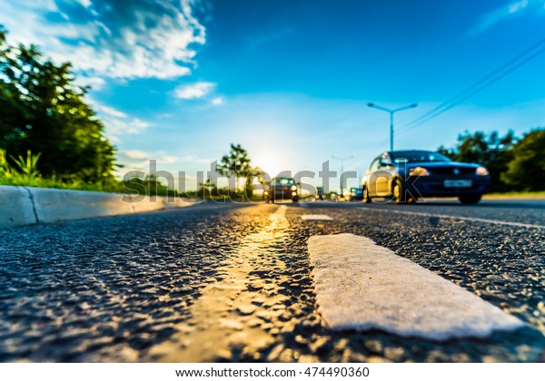 Sunset in the country, the cars on the highway\
traveling toward. Wide angle view of the level of the dividing\
line, image in the blue\
tones