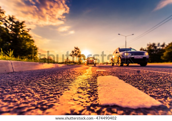 Sunset in the country, the cars on\
the highway traveling toward. Wide angle view of the level of the\
dividing line, image in the orange-purple\
toning