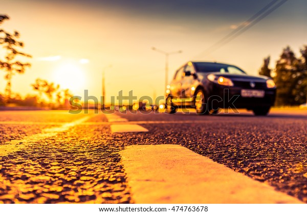 Sunset in the country, the stream of\
cars passing by on the highway. Wide angle view of the level of the\
dividing line, image in the orange-purple\
toning