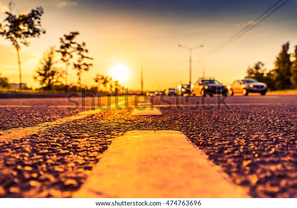 Sunset in the country, the stream of
cars passing by on the highway. Wide angle view of the level of the
dividing line, image in the orange-purple
toning