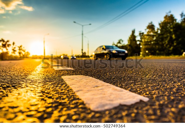 Sunset in\
the country, the stream of cars passing by on the highway. Wide\
angle view of the level of the dividing\
line
