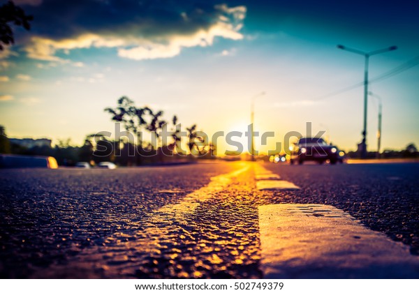 Sunset in the country, the stream of cars\
passing by on the highway. Wide angle view of the level of the\
dividing line, image\
vignetting