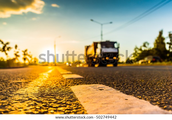 Sunset in the country, the\
truck on the highway. Wide angle view of the level of the dividing\
line