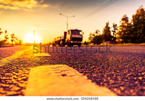 Sunset in the country, the truck on the highway.\
Wide angle view of the level of the dividing line, image in the\
orange-purple toning