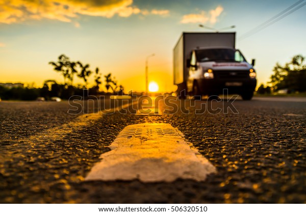 Sunset in the country, the\
truck on the highway. Wide angle view of the level of the dividing\
line