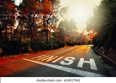 Sunset countryside asphalt road with finish line message on the floor.
