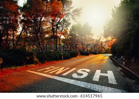 Sunset countryside asphalt road with finish line message on the floor.
