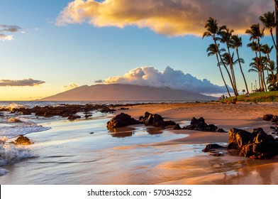 The sunset creates a warm glow on a beach in Maui.
