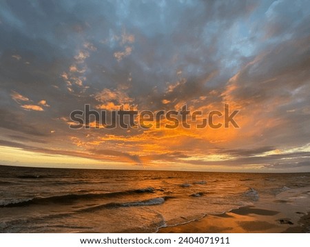 sunset at danish beach with orange clouds that looks like fire in the sky on a beautiful summer evening