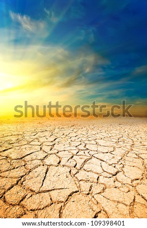 Sunset in the desert against the ground with cracks