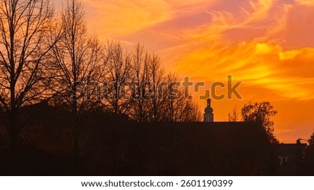 Sunset with dramatic clouds and a church silhouette at Alburg, Straubing, Bavaria, Germany