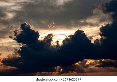 Sunset in a dramatic sky with the rays of a dream piercing through the dark clouds against the background of the city. Bright epic sky. Dramatic evening light and fiery orange sunset.