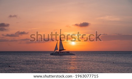 sunset at eagle beach in aruba in the caribbean with catamaran in composition