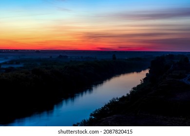 Sunset at evening sunrise over the river.Morning dawn.Late evening.Evening sunset.Evening golden hours and nightfall.Glowing pink sky.Heavenly horizon line.Night skyline with red clouds.View nature