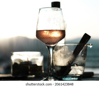 Sunset Glass Of Wine, Ice , Bottle Of Water, Sun, Grey Dark Tones, Against Light Shot, Evening Apperitive Drink, Sun Blink In A Glass