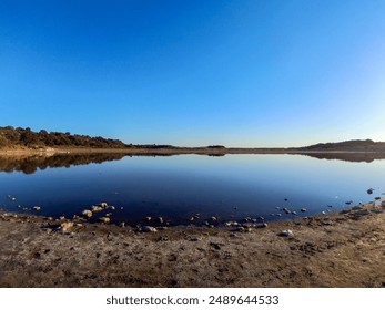 sunset at the lake beautiful, Trees reflecting in calm river water under vivid blue sky with copy space. trees and clouds reflecting off glassy water surface. Blue lake and lakeshore in sunny evening - Powered by Shutterstock