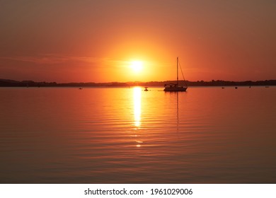 Sunset at lake "Chiemsee". The silhouette of a sailboat is visible.
