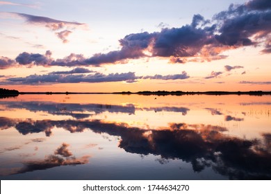 Sunset lake water horizon landscape. Sunset lake water. Sunset lake landscape. Sunset lake with cloudy sky at summer and water reflection.