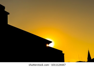 The sunset leaking through the shape of a rooftop.