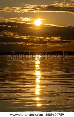 Sunset light bathes Luleå’s waterfront in warm gold during summer, with shimmering water reflections, pastel sky hues, and tranquil archipelago silhouettes under Nordic twilight.