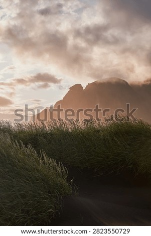 Sunset light filtering through clouds over black sand dunes and Vestrahorn mountain range at Stokksnes - Iceland