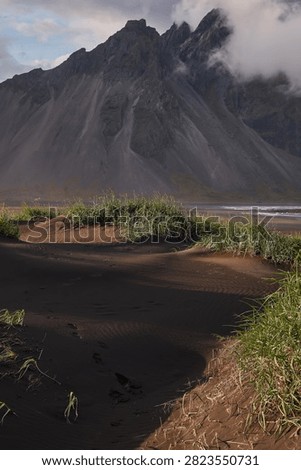 Sunset light filtering through clouds over black sand dunes and Vestrahorn mountain range at Stokksnes - Iceland
