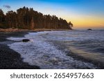 Sunset light reflects on waves and a sea stack along the forested shore of Ruby Beach, Washington State
