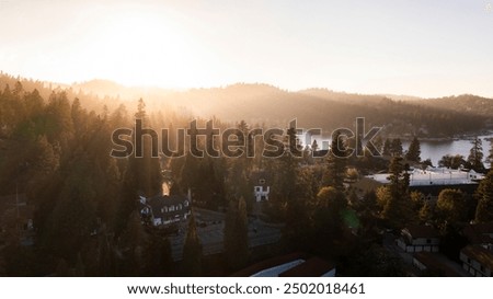 Sunset light streams through pine trees and mountains of Lake Arrowhead, California, USA.